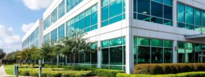 Commercial building exterior and landscaping in Plano, TX needing soft washing.